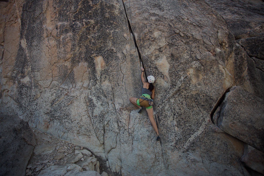 A climber ascending a granite rock face